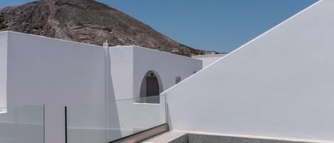 A rooftop terrace with a pool, two towels, and a mountain in the background.
