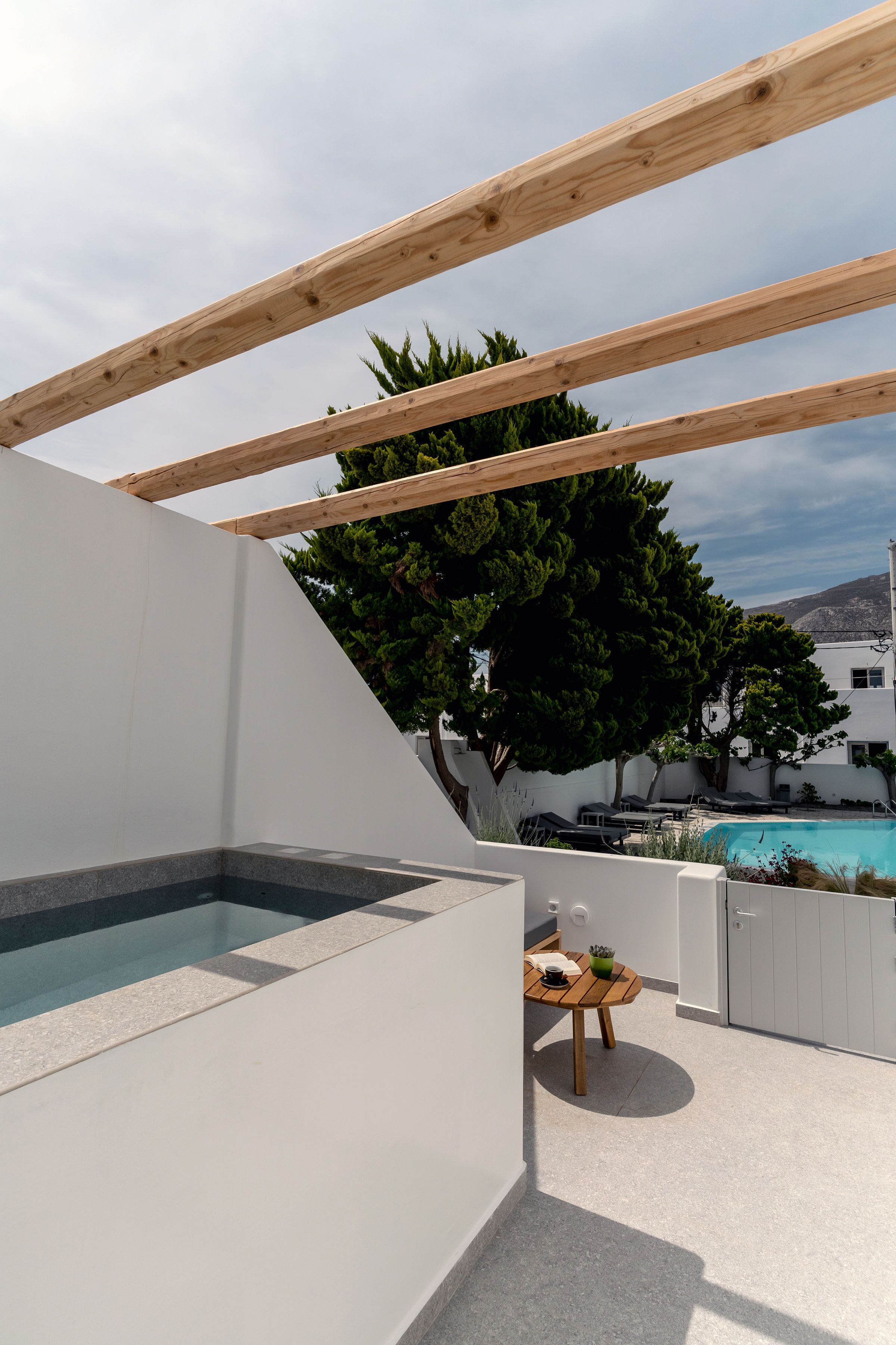 Terraza en la azotea con piscina, vigas de madera y una mesa con asientos exteriores.