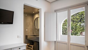 Un baño con lavamanos, espejo y televisor montado en la pared.