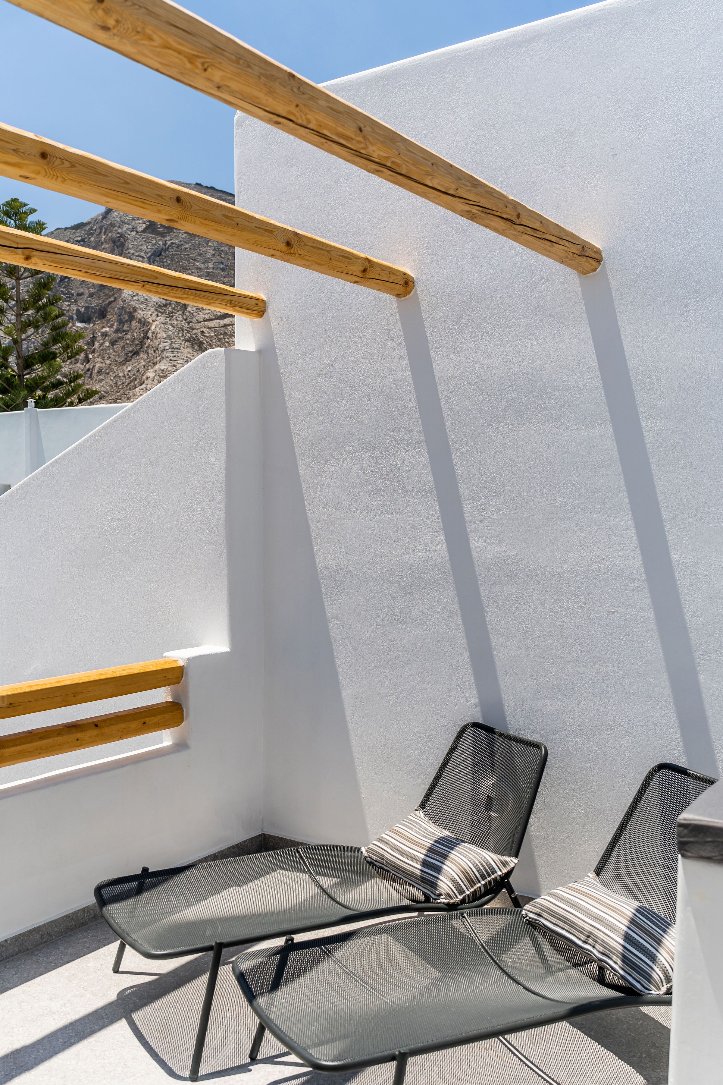 A balcony with two metal chairs and a wooden beam structure.