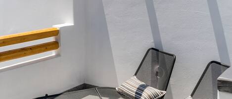 A balcony with two metal chairs and a wooden beam structure.