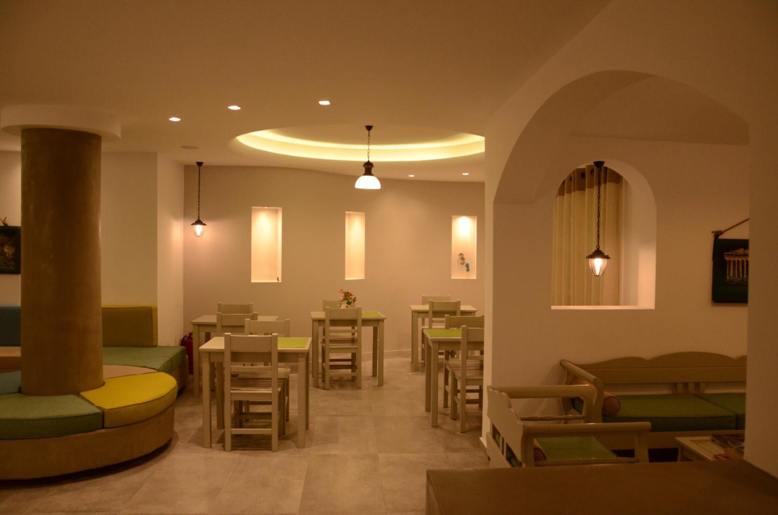 A cozy, well-lit dining area with round tables and chairs, a large pillar, and a curved seating area.