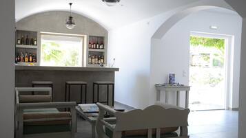 Ein Zimmer mit Bar, Sitzgelegenheiten und Blick auf Grünflächen.
