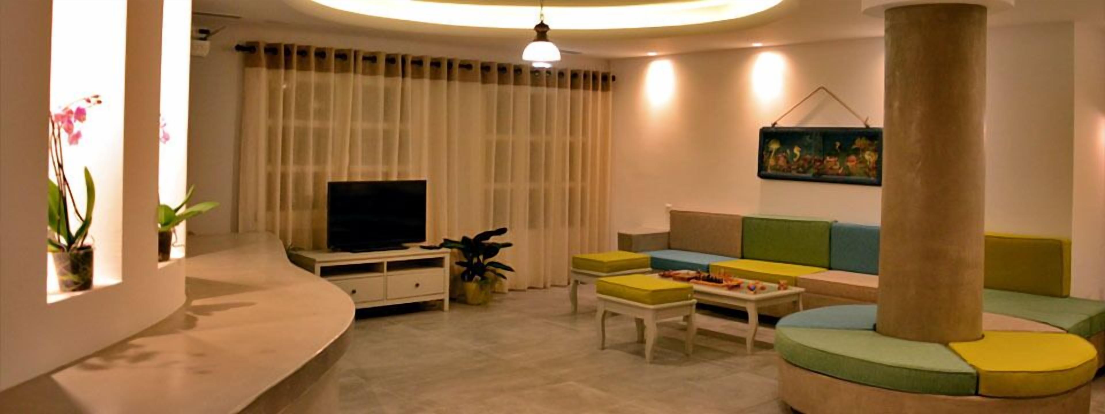 A modern living room with a curved sofa, a flat-screen TV, and a large pillar.