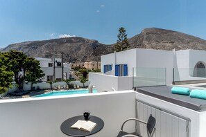 Eine Dachterrasse mit Pool, weiße Gebäude und ein Berg im Hintergrund.