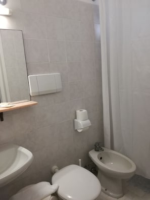 Une salle de bain équipée de toilettes, d’un bidet et d’un lavabo.