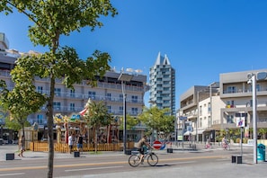 Une scène de rue avec un manège, un immeuble de grande hauteur et un cycliste.
