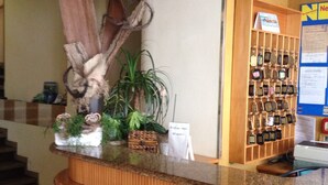 Un comptoir d’accueil avec un revêtement en bois, une composition florale et une sélection de porte-clés.