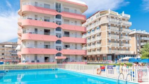 Un hôtel à plusieurs étages, doté de balcons, d’une piscine et d’une clôture blanche.