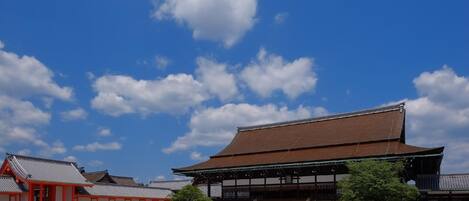 Um edifício japonês tradicional com um amplo pátio aberto, estruturas de madeira e um céu azul límpido.