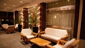 A lobby with wicker furniture, a potted plant, and a sign on the wall. - Hotel Majorca (Riccione)