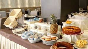A buffet with various food items including a pineapple, donuts, and a chocolate cake. - Hotel Majorca (Riccione)