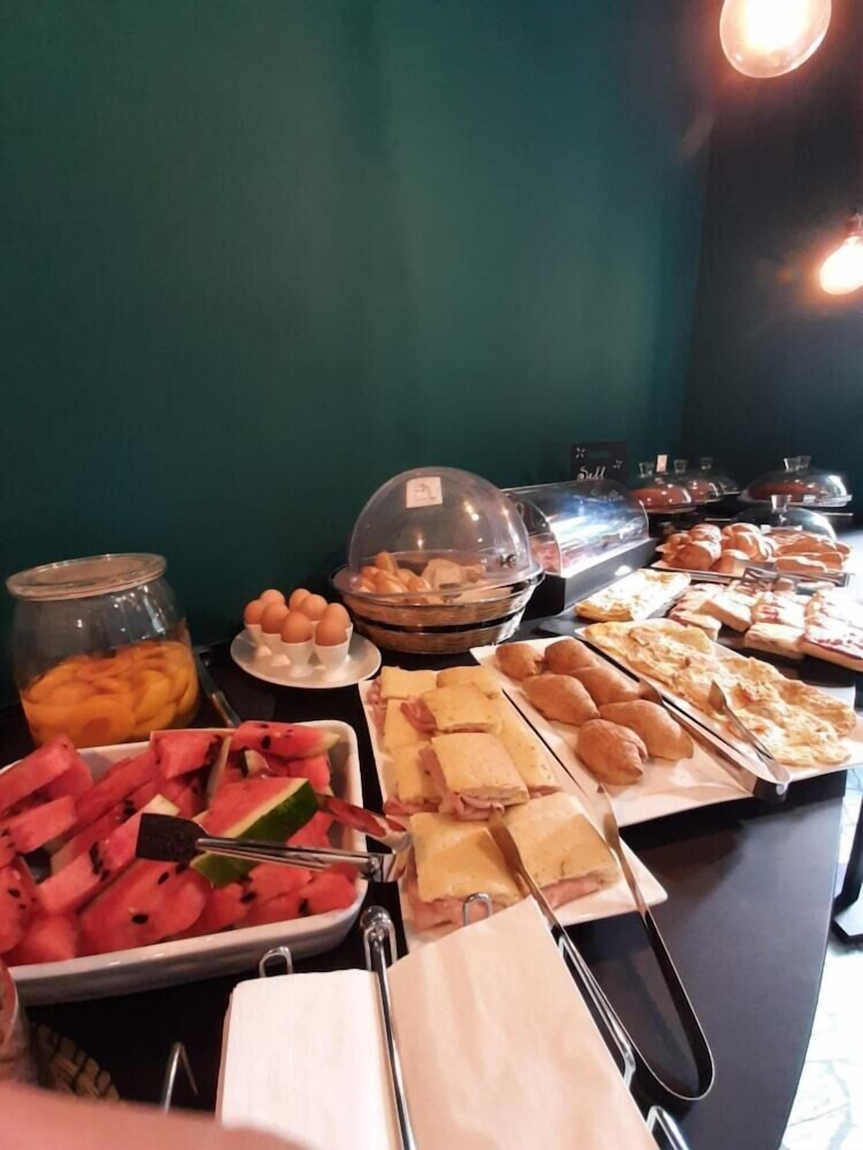 Un buffet con diverse pietanze, tra cui panini, pasticcini e frutta.