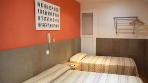 Una camera d'albergo con due letti, un portasciugamani e una parete con un cartello.
