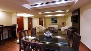 A modern dining area with a glass table, wooden chairs, a white sofa, and a TV mounted on the wall. - Holiday Inn Mexico City-plaza Universidad (Mexico City)