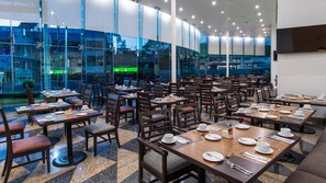 A restaurant with multiple tables and chairs, large windows, and a view of the outside. - Holiday Inn Mexico City-plaza Universidad (Mexico City)