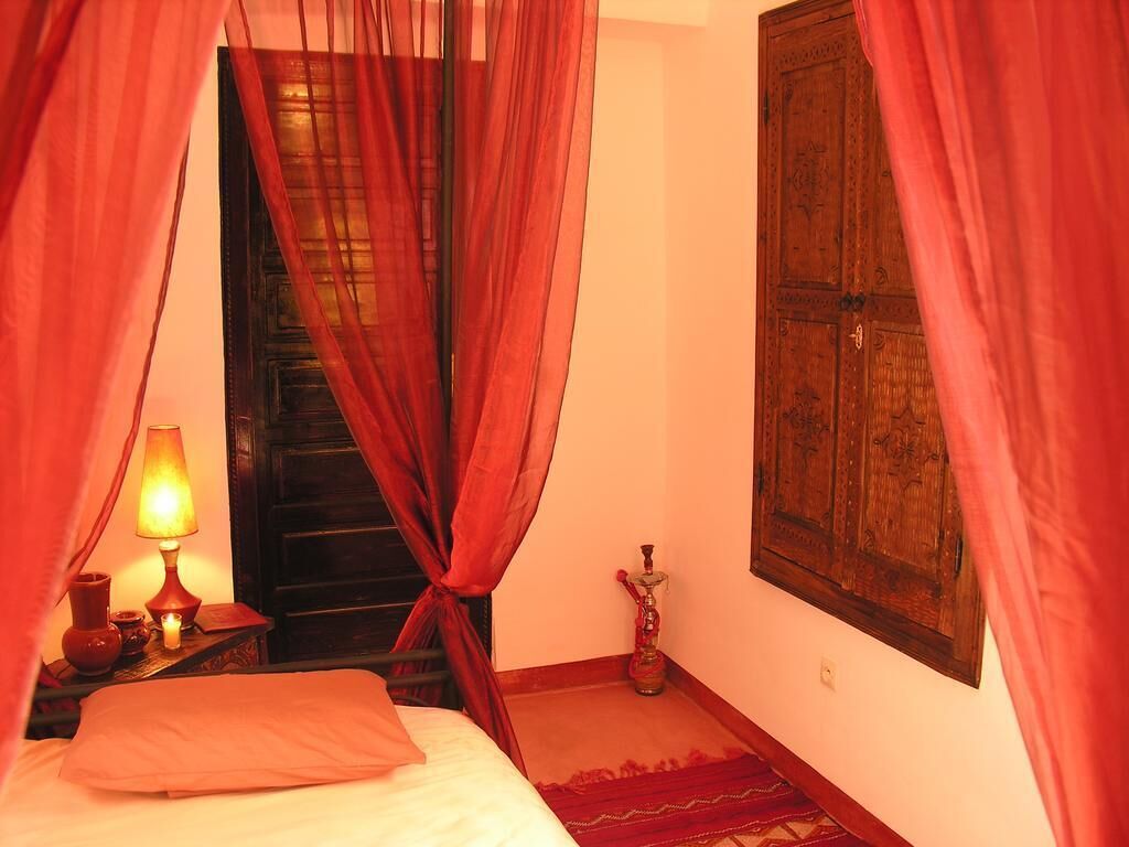 Una habitación con una cama, una lámpara, un narguile y un armario de madera.