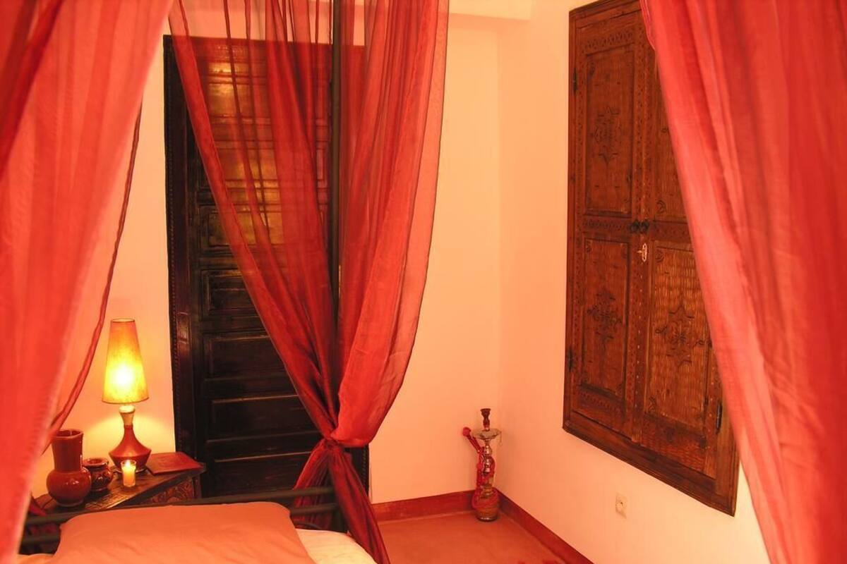 Een kamer met een bed, een lamp, een shisha en een houten kast.