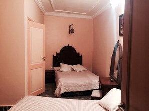 A bedroom with a double bed, a nightstand, a mirror, and a door. - Hotel Al Mamoun (Casablanca)