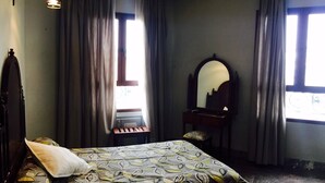 A bedroom with a bed, a dresser, a mirror, and a window with curtains. - Hotel Al Mamoun (Casablanca)
