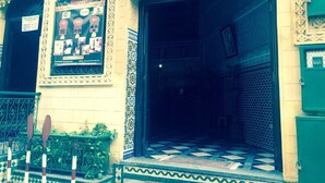 A building entrance with ornate architectural details, a tiled entrance area, and a poster advertising rooms and breakfast. - Hotel Al Mamoun (Casablanca)