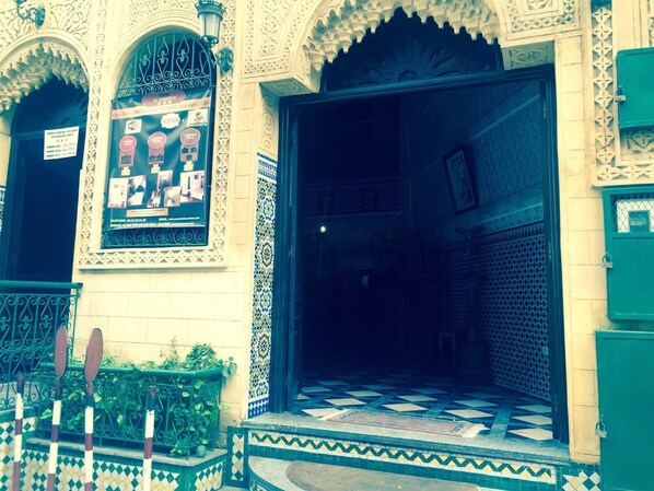 A building entrance with ornate architectural details, a tiled entrance area, and a poster advertising rooms and breakfast. - Hotel Al Mamoun (Casablanca)