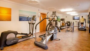 Et fitnesscenter med løbebånd, crosstrainere og et tv-skærm.