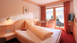 A hotel room with a bed, desk, chair, TV, and a window with curtains. - Eggerwirt (SÖLL)