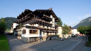 A traditional Alpine hotel with multiple balconies adorned with flowers, a restaurant, and a visible staircase leading to the upper floors. - Eggerwirt (SÖLL)