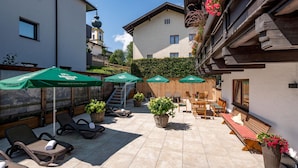 A patio area with sun loungers, green umbrellas, and potted plants. - Eggerwirt (SÖLL)