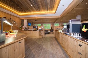 A spacious kitchen with wooden cabinets, a central island, and a television. - Hotel Lärchenhof (Lermoos)