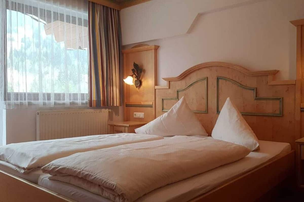 A double bed with two pillows, a nightstand with a lamp, and a wooden headboard.
