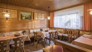 A cozy restaurant with wooden walls, multiple tables, and chairs. - Gerlinde Feichter (Soell)