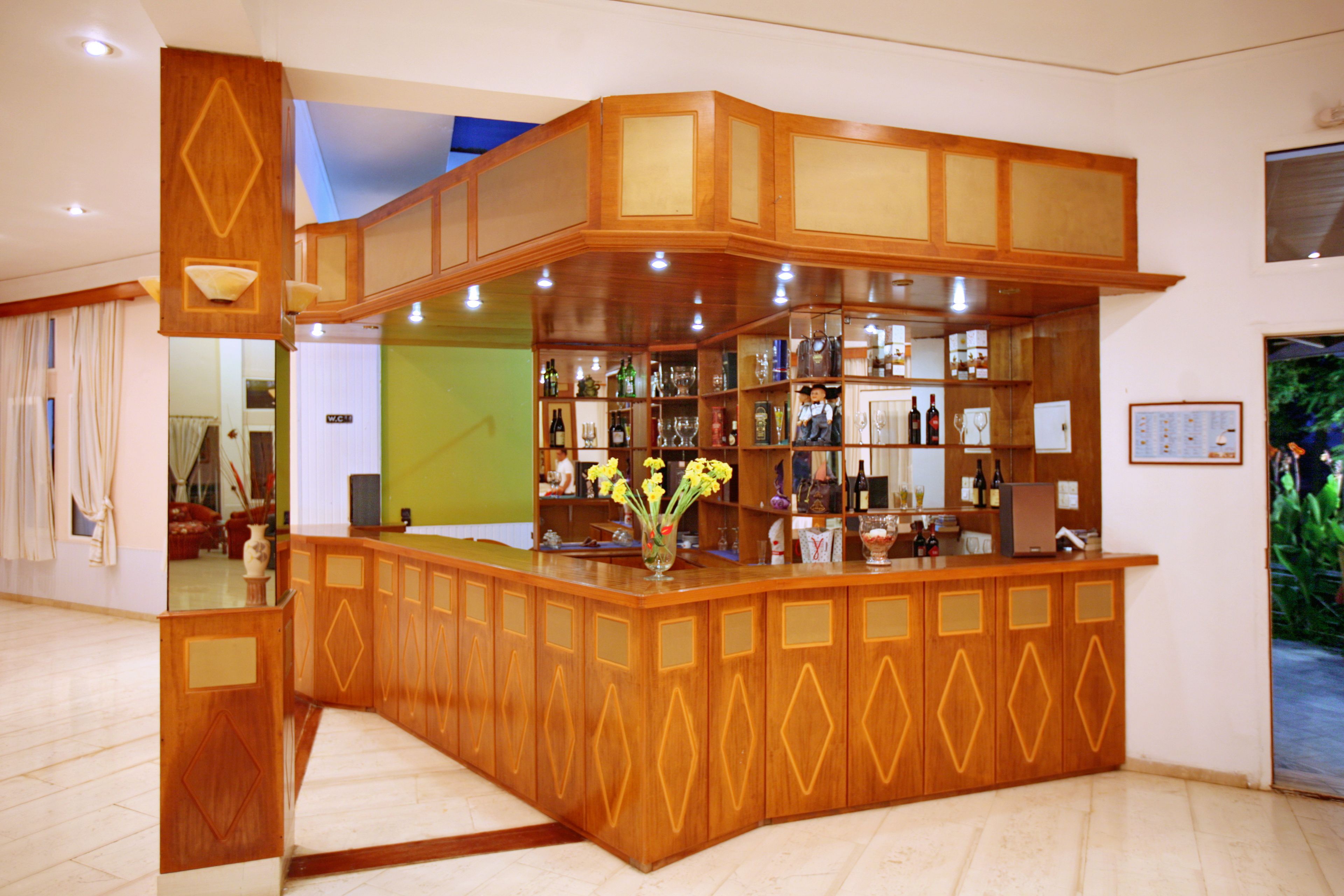 A bar area with wooden cabinets and shelves displaying various bottles and glasses.