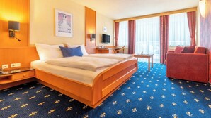 Hotelkamer met een bed, bureau, stoel, televisie en een raam met gordijnen.