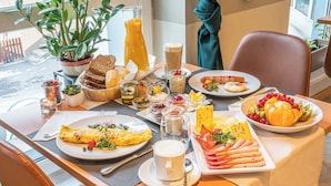 Een ontbijtsetting met diverse gerechten, zoals een omelet, croissants en fruit.