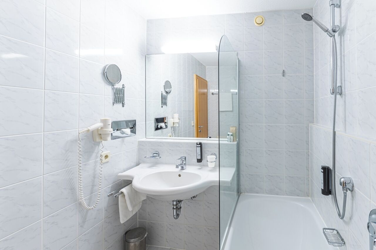 A modern bathroom with a glass-enclosed shower, a white sink with a mirror, and a toilet.