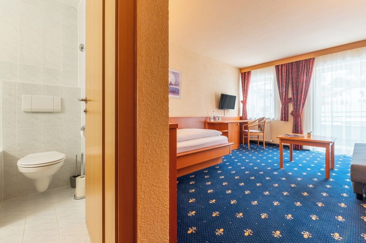 Une chambre d’hôtel équipée d’un lit, d’un bureau, d’une chaise, d’une télévision et d’une salle de bain avec des toilettes et une douche.
