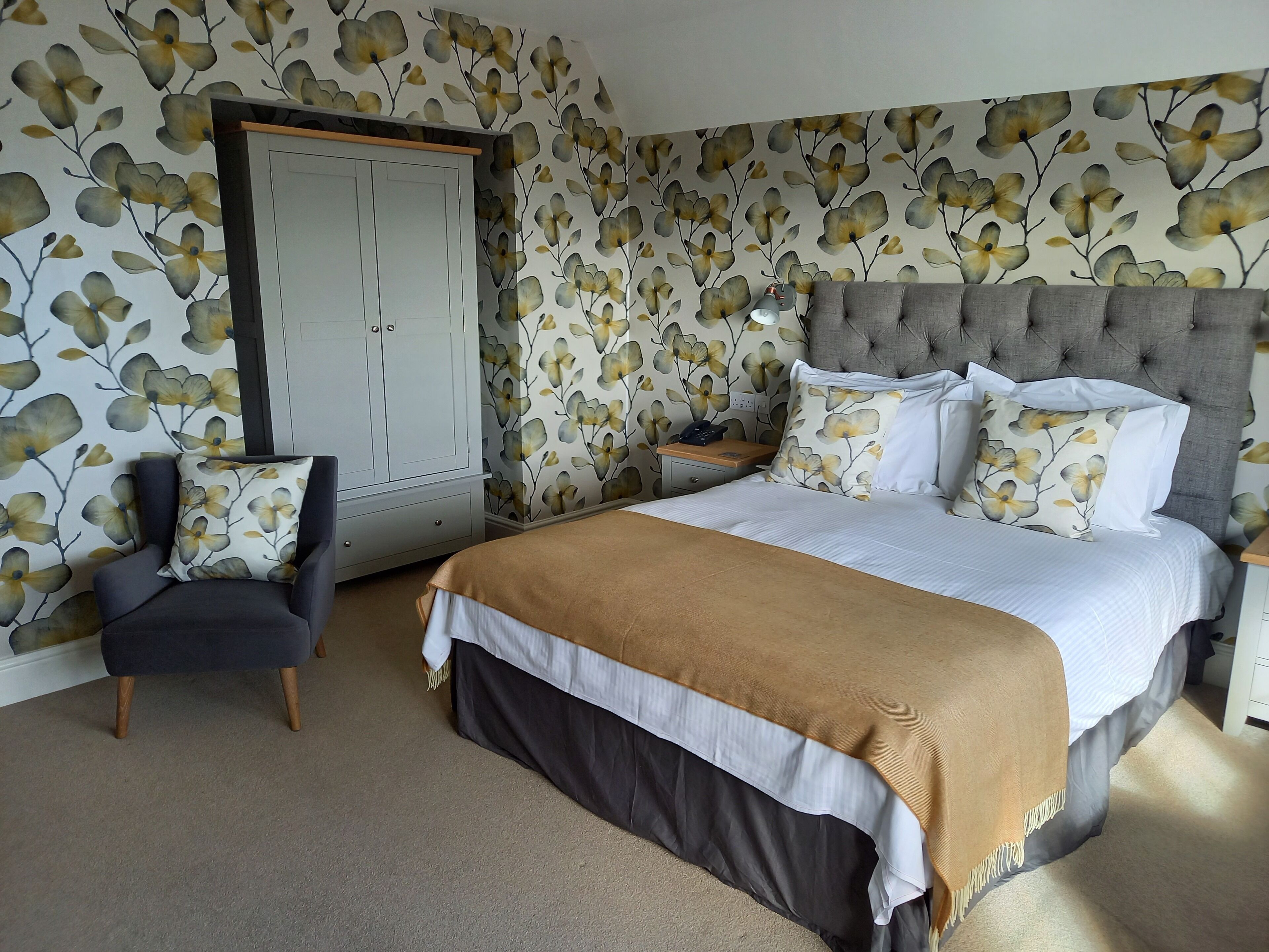 A bedroom with a bed, a chair, a wardrobe, and a nightstand.