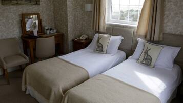 A hotel room with two beds, a desk, a chair, a mirror, and a window with curtains.