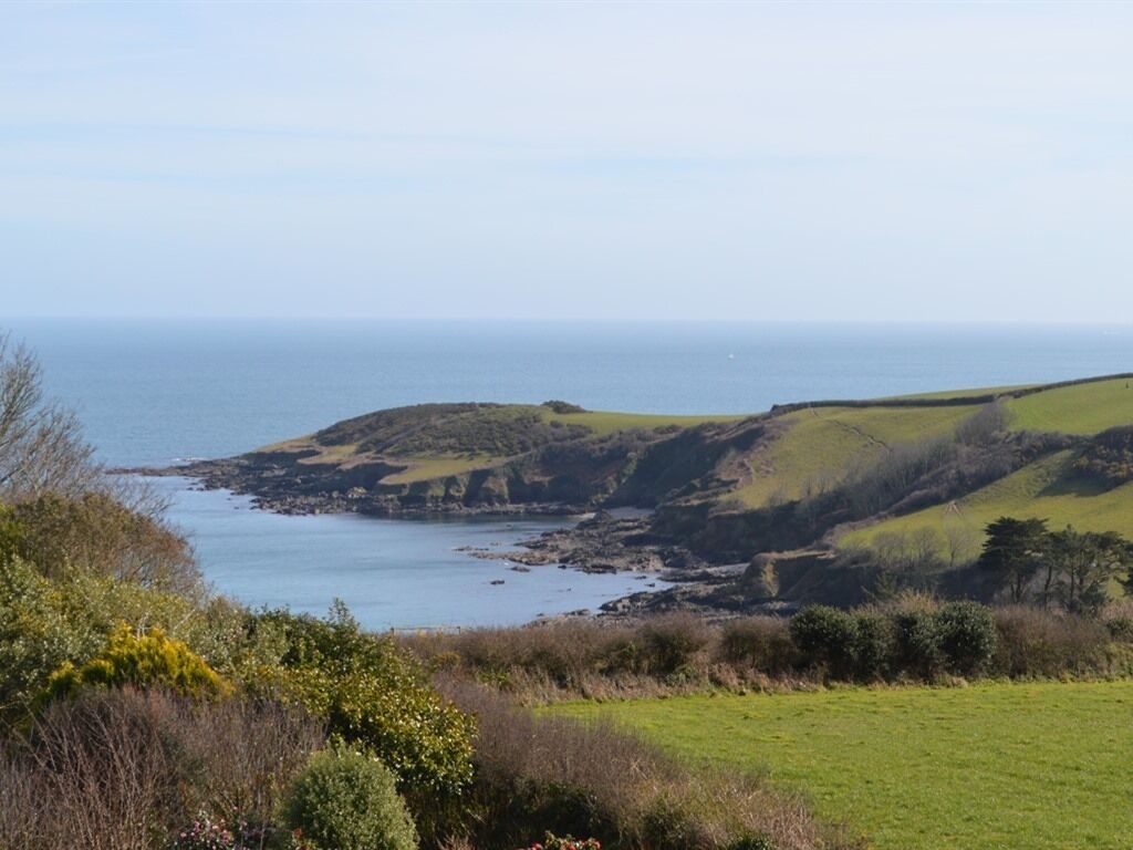 A coastal landscape with grassy fields and rocky cliffs.