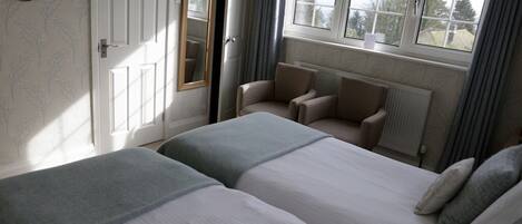 Un dormitorio con dos camas, una silla, una ventana y una puerta.