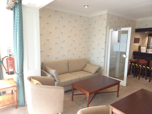 Ein Wohnzimmer mit einem beigen Sofa, einem Holztisch und einer Wand mit Muster.