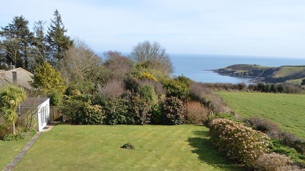 A coastal property with a well-maintained lawn, dense shrubbery, and a view of the sea. - Trelawne Hotel (Falmouth)