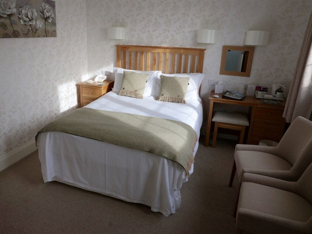 Une chambre d’hôtel bien aménagée, avec un grand lit, des tables de chevet, une chaise et un bureau.