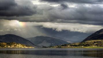A lake with mountains in the background and a rainbow in the sky.