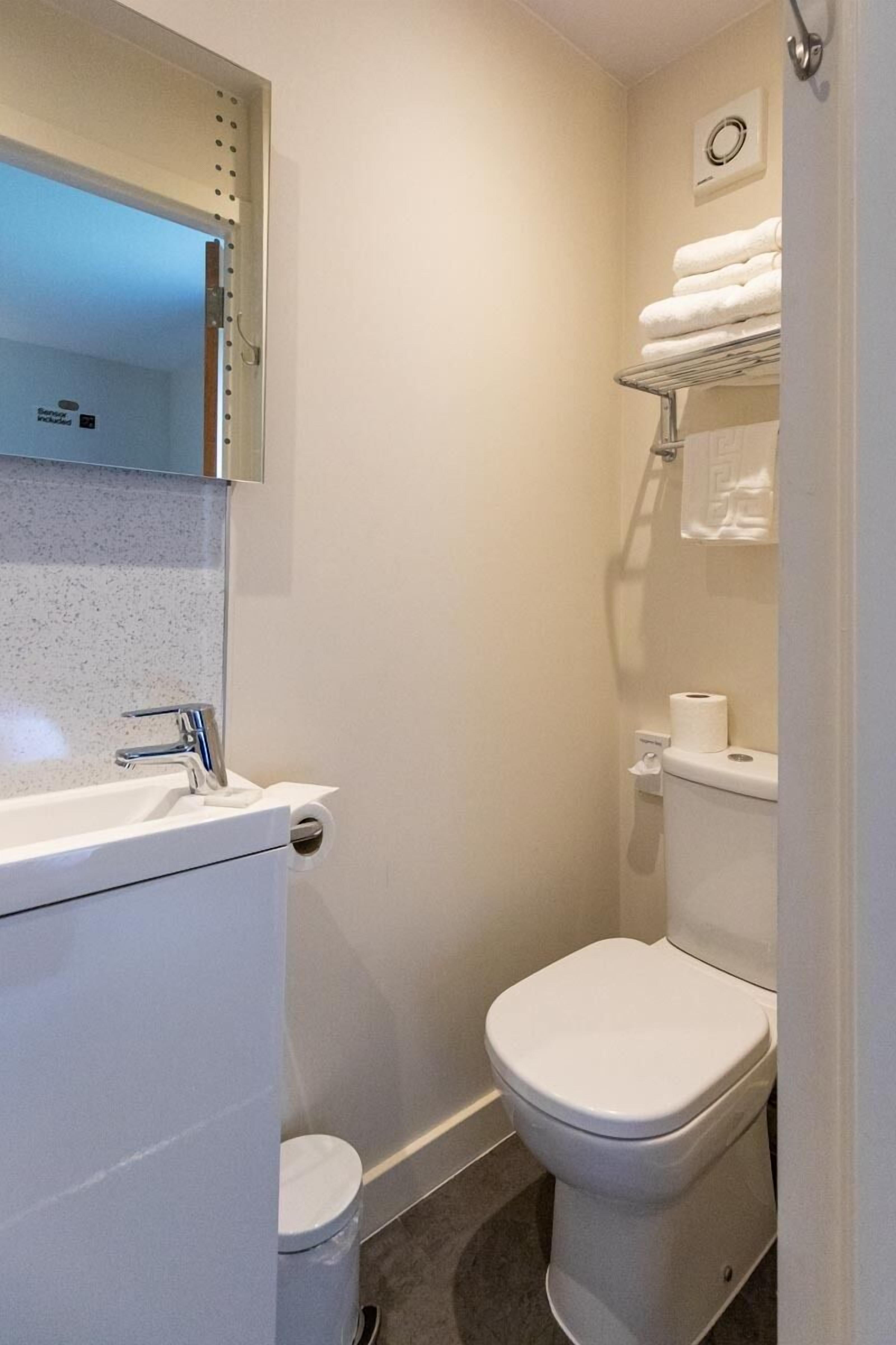 Een kleine badkamer met een wit wastafel, toilet en handdoekhouder.