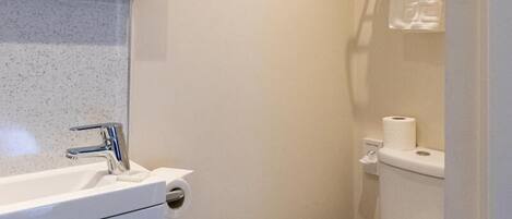 A compact bathroom with a white sink, toilet, and a towel rack.