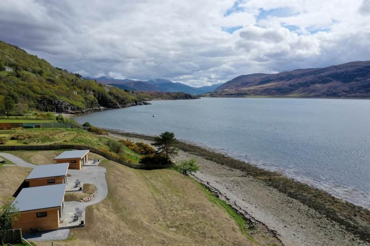 Una propiedad frente al lago con varias cabañas, un espacio con césped y vistas al lago y las montañas.