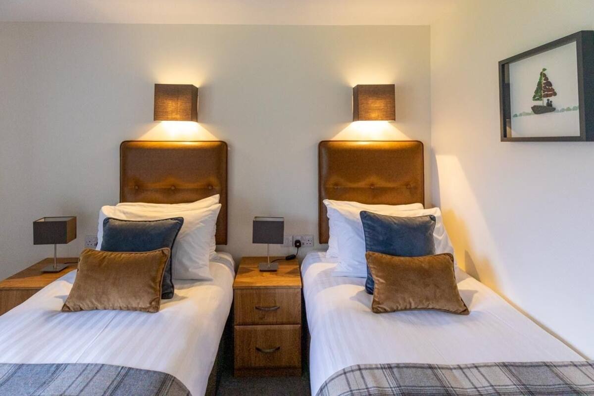 Habitación doble con dos camas, cada una con cabecero y mesitas de noche de madera.